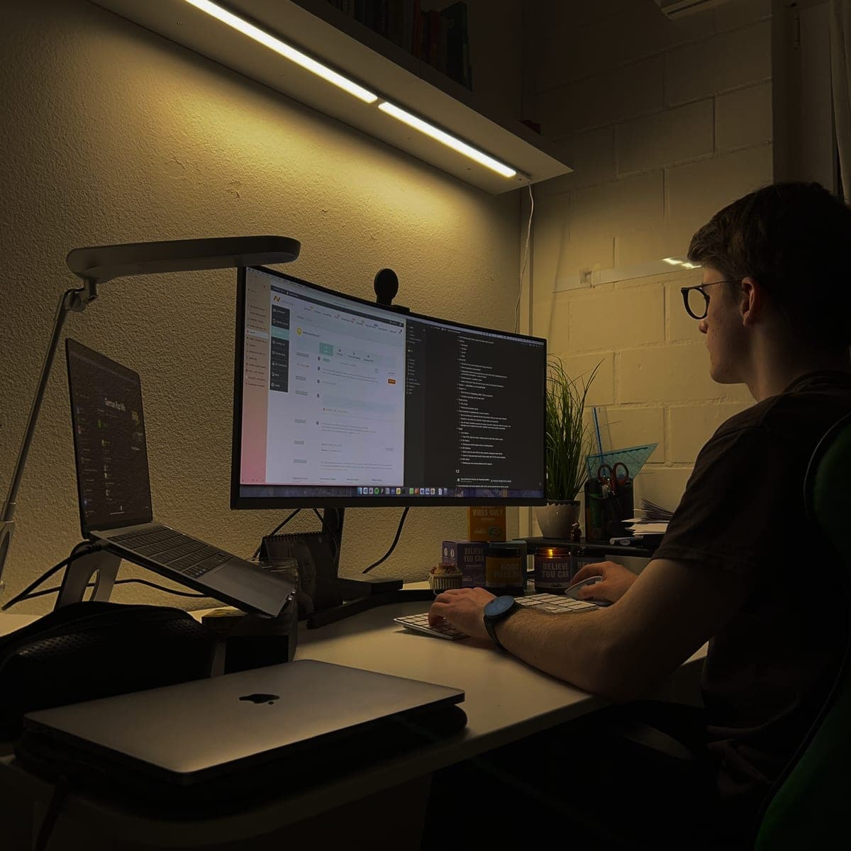 Jannis arbeitet abends am Schreibtisch vor zwei Bildschirmen.
